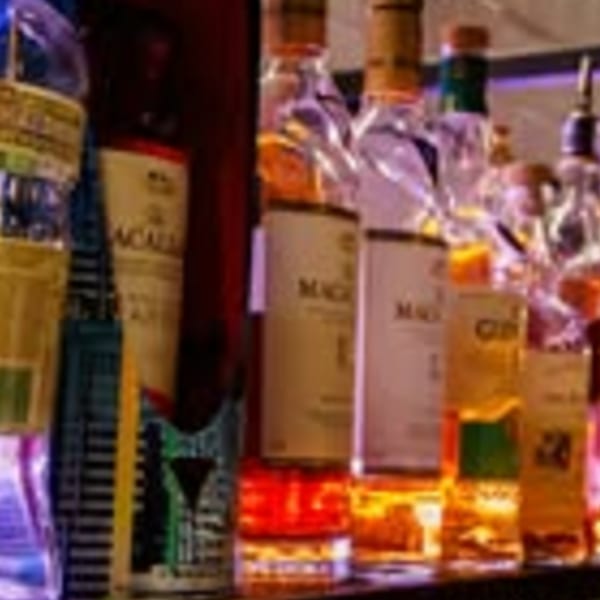 Bottles of liquor, including Macallan, illuminated on a bar shelf.