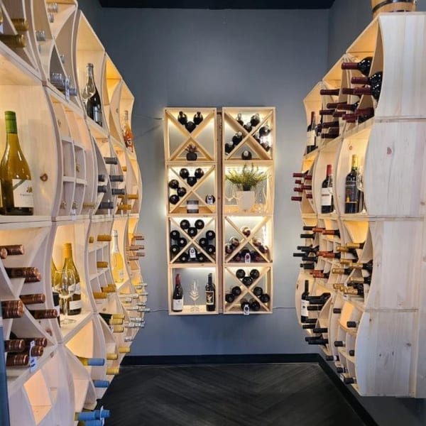 A wine cellar with two tall wooden racks filled with wine bottles and a central display.