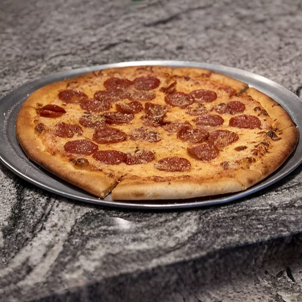 A whole pepperoni pizza with a slice removed, on a metal tray, resting on a granite countertop.